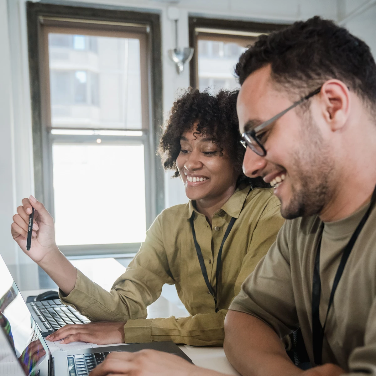 Deux professionnels souriants travaillant ensemble sur un site internet
